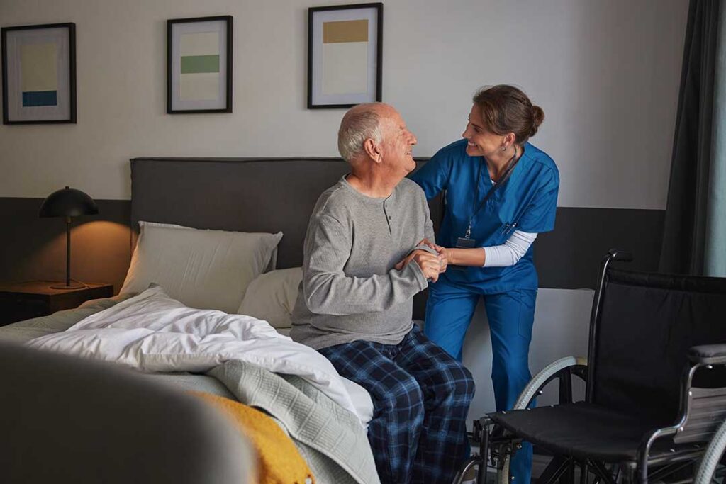 Older adults talking together in a bright assisted living common room with books and natural light.